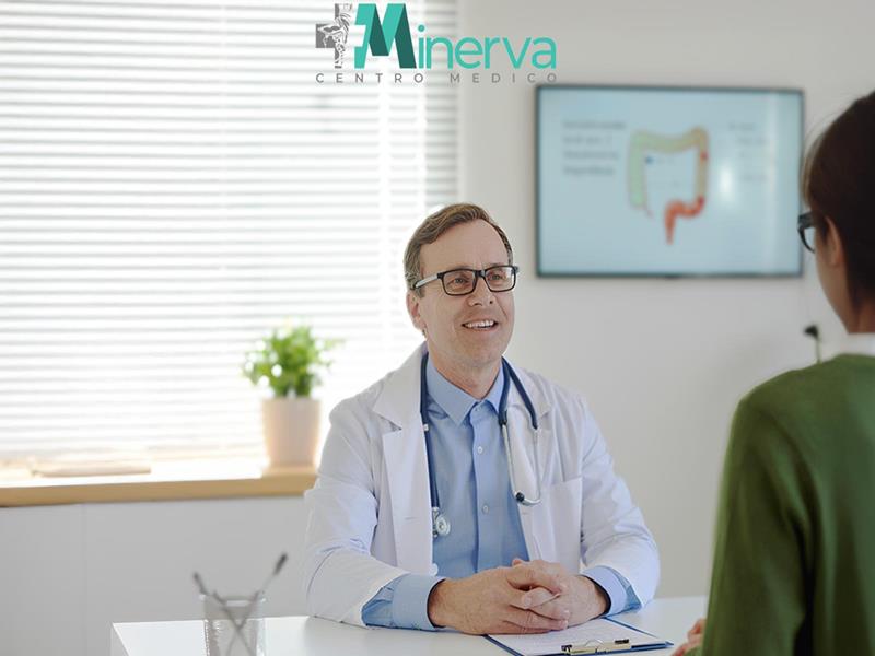 Gastroenterologo che parla con la paziente per una visita gastroenterologica con illustrazione dell'apparato digerente